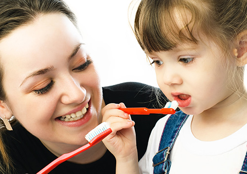 mother teaching child to brush teeth