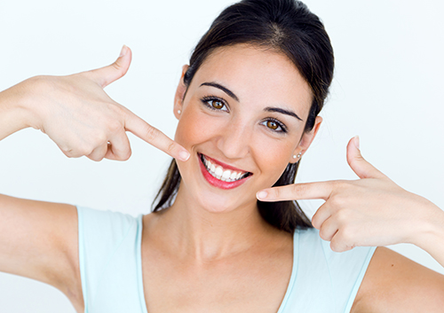 young woman pointing to her smile