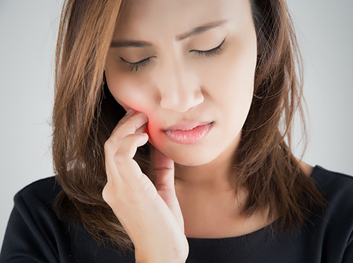 woman with eyes closed showing signs of tooth pain